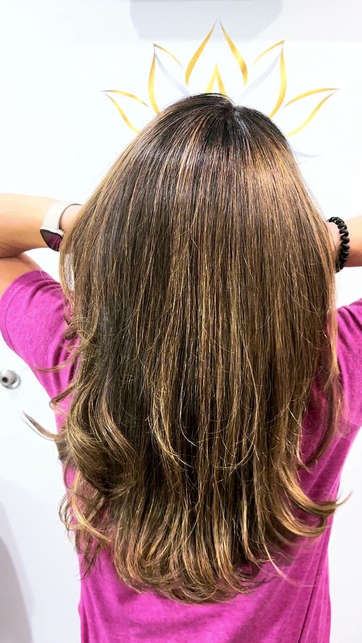 Caramel balayage with soft layers, turned in the light at the lotus wall