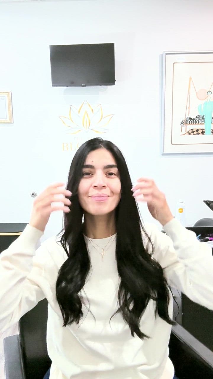 A client smiling with her long black waves
